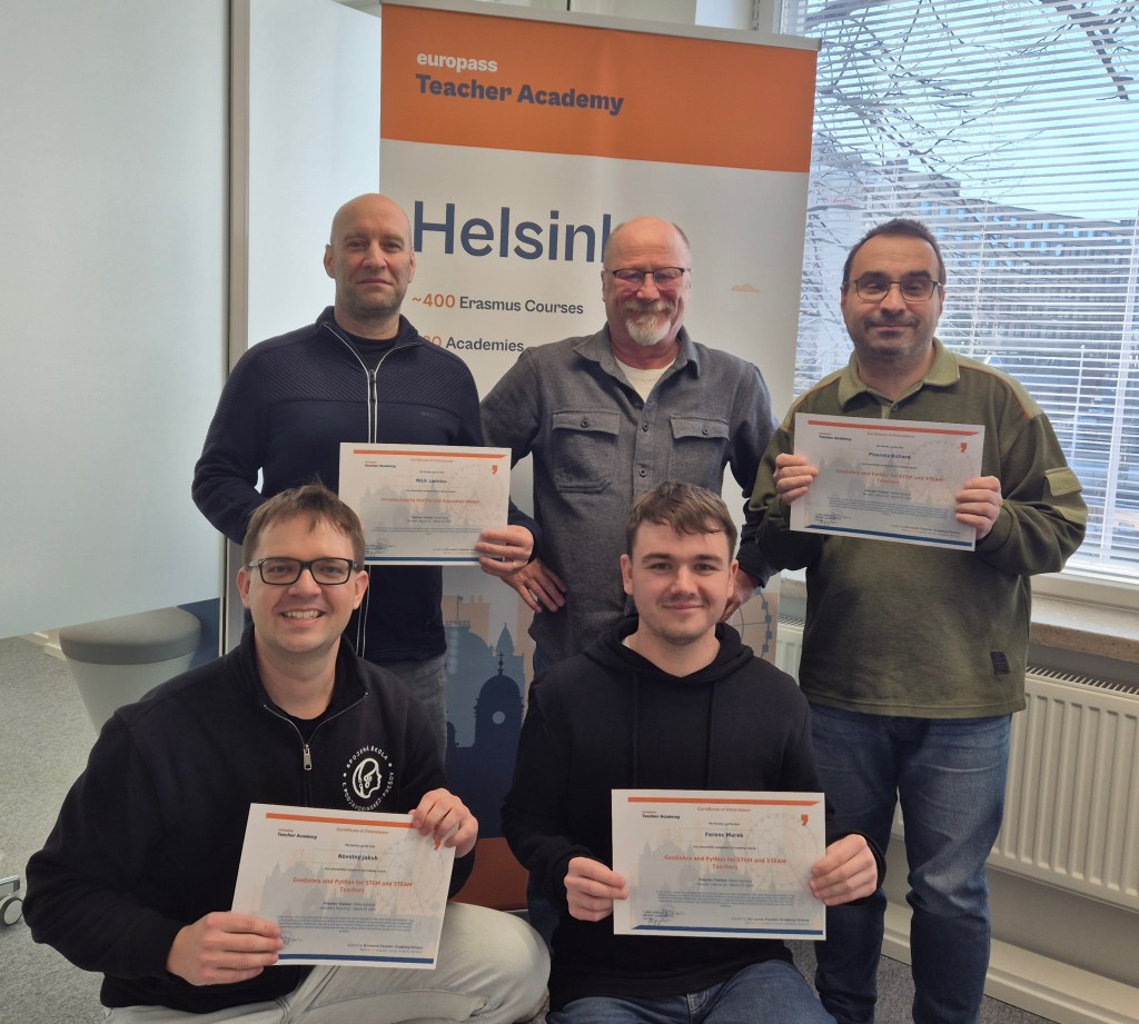 Viisi miestä poseeraa yhdessä, jokaisella on kädessään todistus. Taustalla on Europass Teacher Academy -taustalehti ja ikkuna.